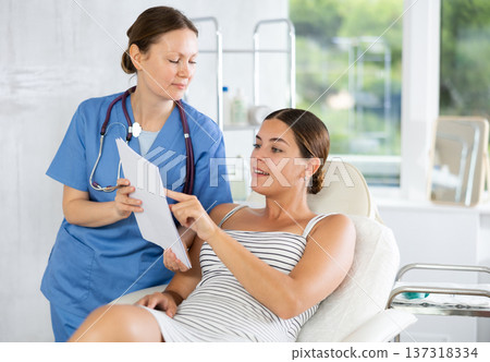 Adult female doctor shows contract to patient Adult female doctor shows contract to patient 137318334