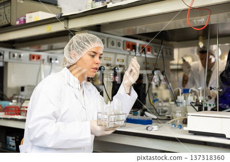 Female pharmacist researcher holding tripod and waiting for color change in test tube while conducting experiment in laboratory Female pharmacist researcher holding tripod and waiting for color change in test tube while conducting experiment in laboratory 137318360