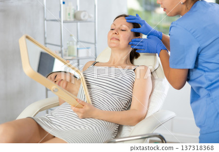 Young woman cosmetologists examines face of female patient 137318368
