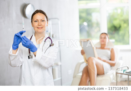 Adult female doctor posing with syringe in medical room 137318433