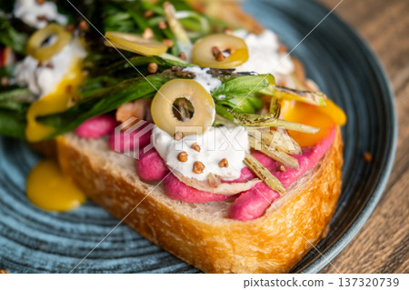 Brunch toast. Spicy food. Appetizing sandwich with creative vegetable bright toppings. Beetroot sauce roasted greens olives on bread. Brunch toast. Spicy food. Appetizing sandwich with creative vegetable bright toppings. Beetroot sauce roasted greens olives on bread. 137320739