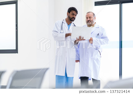Concentrated mature and young male doctors in white medical uniforms look at laptop computer and discuss patient anamnesis together. team brainstorming make decision concept. Concentrated mature and young male doctors in white medical uniforms look at laptop computer and discuss patient anamnesis together. team brainstorming make decision concept. 137321414
