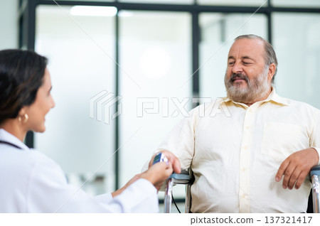 Doctor uses finger pulse oximeter measuring patient man while he sitting in a wheelchair, elderly health checkup, happiness. 137321417
