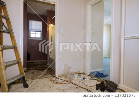 Renovation is taking place at home with ladder, tools, unfinished walls in hallway. 137321573