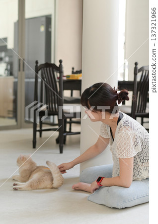 Calm peaceful asian woman sitting comfortable on floor cushion at home improving daily mental health and lifestyle wellness by gently touching friendly cat pet feeling relaxed happy 137321966