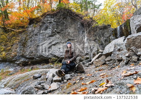 Russian solo traveller sitting on rock with smartphone and contemplating autumn forest and nature at Kravtsovskie Waterfalls Far East Russia peaceful travel Russian solo traveller sitting on rock with smartphone and contemplating autumn forest and nature at Kravtsovskie Waterfalls Far East Russia peaceful travel 137322538