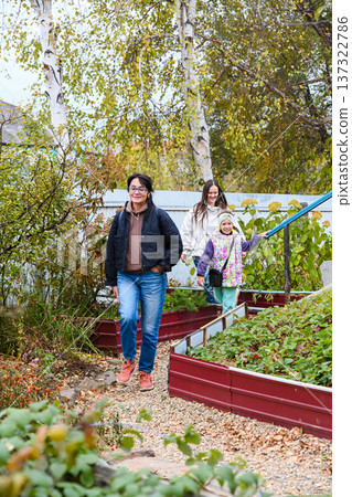 Two Russian women and a child happily walking through a garden in a rural village, enjoying friendship and autumn together, copy space. Two Russian women and a child happily walking through a garden in a rural village, enjoying friendship and autumn together, copy space. 137322786
