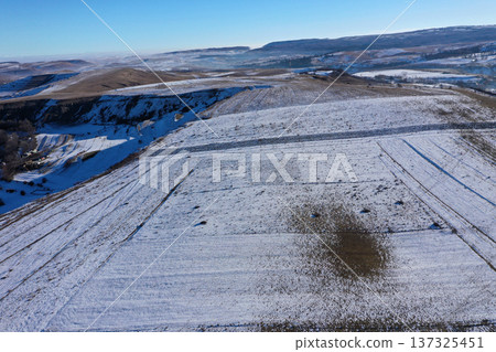 Aerial view of melting snow on hills on a misty sunny day 137325451