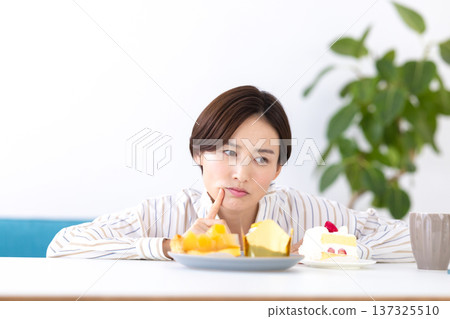 Diet: A woman wondering whether to eat cake Diet: A woman wondering whether to eat cake 137325510
