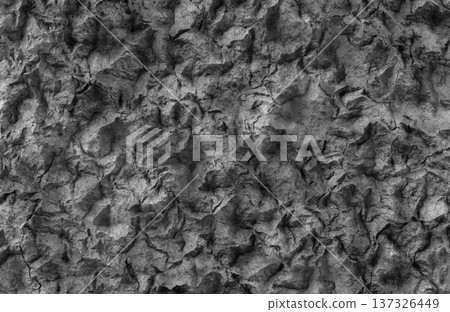 Dark gray rough volcanic rock surface texture with deep crevices and shadows. 137326449