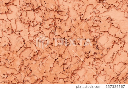 Peeling orange and peach paint layers on weathered surface creating abstract cracked clay texture. 137326567