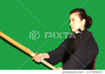 一位身穿防護裝備的老年婦女正在練習劍道 一位身穿防護裝備的老年婦女正在練習劍道 137326815