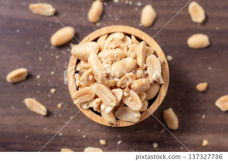 Peanuts in a wooden cup rest on a natural wood floor, creating a warm and rustic food-themed scene. Peanuts in a wooden cup rest on a natural wood floor, creating a warm and rustic food-themed scene. 137327786