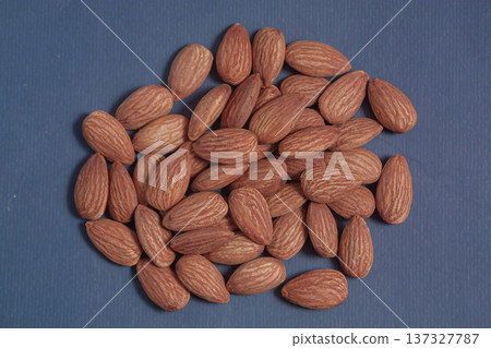 Almonds rest on a simple piece of paper, highlighting their natural texture in a clean minimal scene. Almonds rest on a simple piece of paper, highlighting their natural texture in a clean minimal scene. 137327787