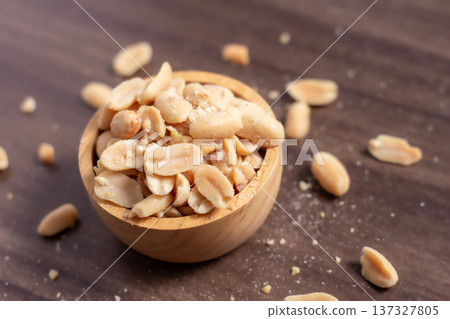 Peanuts in a wooden cup rest on a natural wood floor, creating a warm and rustic food-themed scene. Peanuts in a wooden cup rest on a natural wood floor, creating a warm and rustic food-themed scene. 137327805
