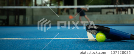 Padel players engage in a competitive match on a blue court 137328025