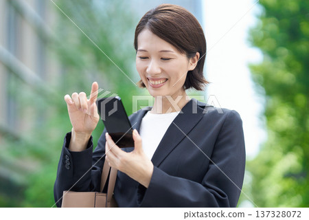 Business woman operating a smartphone Business woman operating a smartphone 137328072