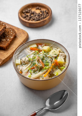 Chicken noodle soup with fresh dill in a yellow bowl on a light textured background Chicken noodle soup with fresh dill in a yellow bowl on a light textured background 137328077