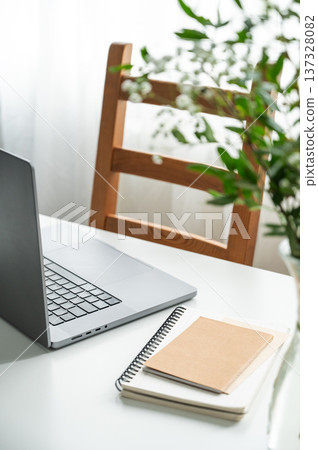 Minimalist workplace with laptop, notepad and flowers on white table. 137328082