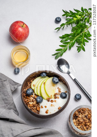 Natural greek yogurt with granola, blueberry and apple in a bowl on a light background 137328087