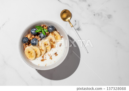 Natural greek yogurt with granola, blueberry and banana in a bowl on a marble background Natural greek yogurt with granola, blueberry and banana in a bowl on a marble background 137328088