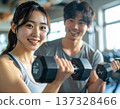 Young woman learning dumbbell exercises from gym trainer 137328466