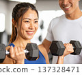 Young woman learning dumbbell exercises from gym trainer 137328471