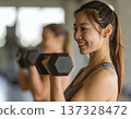 Young woman learning dumbbell exercises from gym trainer 137328472