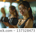 Young woman learning dumbbell exercises from gym trainer 137328473