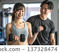 Young woman learning dumbbell exercises from gym trainer 137328474