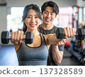 Young woman learning dumbbell exercises from gym trainer 137328589