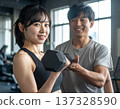 Young woman learning dumbbell exercises from gym trainer 137328590