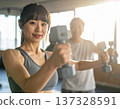 Young woman learning dumbbell exercises from gym trainer 137328591