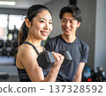 Young woman learning dumbbell exercises from gym trainer 137328592