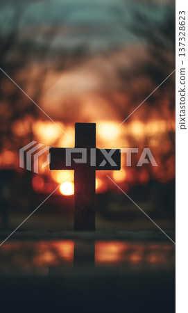 Silhouetted cross stands in twilight's glow. Warm sun sets behind blurred trees. Reflective surface mirrors the cross. Dusk bathes scene in soft orange hues. Stillness radiates from quiet monument Silhouetted cross stands in twilight's glow. Warm sun sets behind blurred trees. Reflective surface mirrors the cross. Dusk bathes scene in soft orange hues. Stillness radiates from quiet monument 137328623