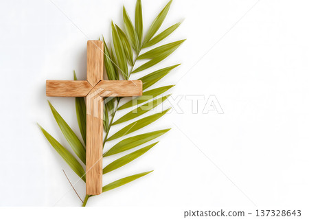Simple wooden cross rests beside green palm fronds. Minimalist composition against clean white background. Natural textures highlight religious symbolism. Cross and leaves suggest themes of faith Simple wooden cross rests beside green palm fronds. Minimalist composition against clean white background. Natural textures highlight religious symbolism. Cross and leaves suggest themes of faith 137328643