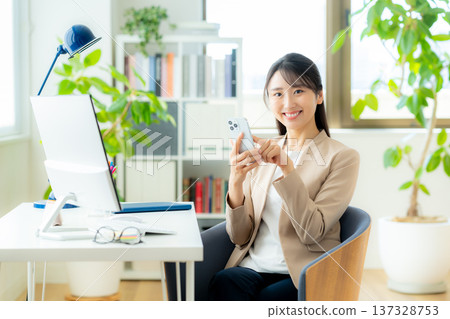 Business woman using a smartphone in the office Business woman using a smartphone in the office 137328753