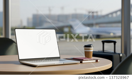 White screen laptop with coffee and books on wooden table and luggage at glass wall in airport cafe. White screen laptop with coffee and books on wooden table and luggage at glass wall in airport cafe. 137328967