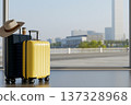 Tourist hat and coffee on black luggage and yellow suitcase aside glass wall at airport. Travel trip 137328968