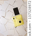 Top view of a yellow instant camera and film photo on the pile of white paper postcard or envelopes. 137328972