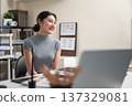 Smiling asian woman office worker or freelancer sitting with laptop and working materials on table. 137329081