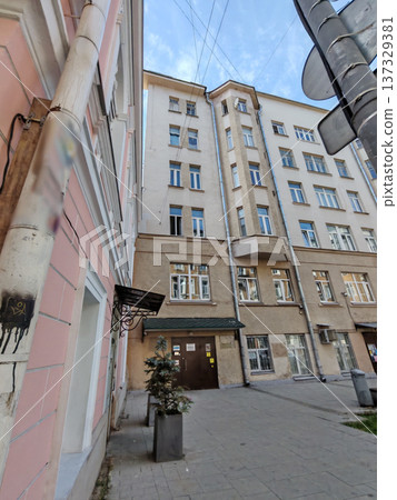 An urban courtyard framed by aged buildings with mixed architectural styles. The worn facades reflect urban decay and highlight the challenges of city infrastructure. An urban courtyard framed by aged buildings with mixed architectural styles. The worn facades reflect urban decay and highlight the challenges of city infrastructure. 137329381