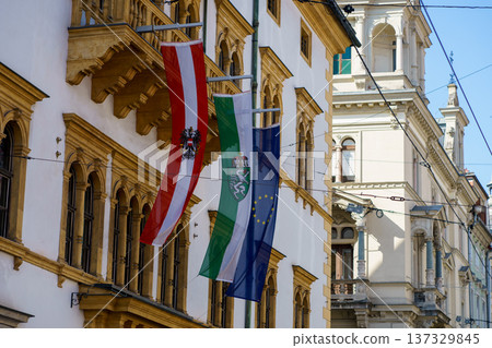 Flags of Austria, Styria region and the European Union hanging on historic architecture. European city center, government building and travel concept Flags of Austria, Styria region and the European Union hanging on historic architecture. European city center, government building and travel concept 137329845