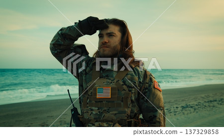 American soldier with long hair salutes on beach near the ocean on Memorial Day American soldier with long hair salutes on beach near the ocean on Memorial Day 137329858