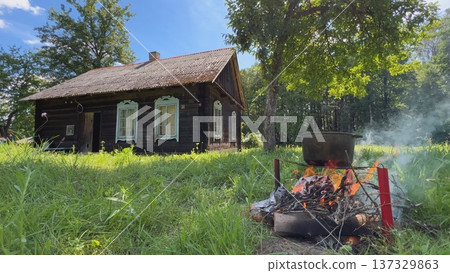 Cooking on campfire near old wooden house in countryside Cooking on campfire near old wooden house in countryside 137329863