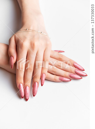Woman's hands showing long pink glitter fingernails manicure with jewelry Woman's hands showing long pink glitter fingernails manicure with jewelry 137330033