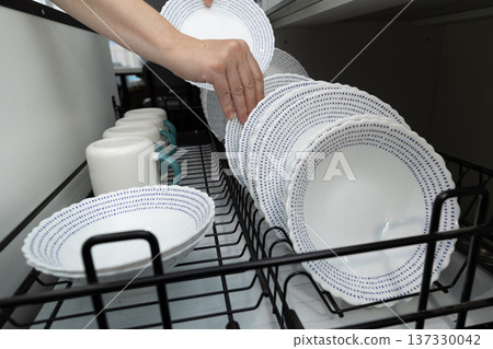Organizing Clean Dishware in a Kitchen Cabinet During the Afternoon Organizing Clean Dishware in a Kitchen Cabinet During the Afternoon 137330042