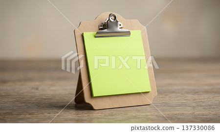 Blank green sticky note on a wooden clipboard with a metal clip, ready for messages 137330086