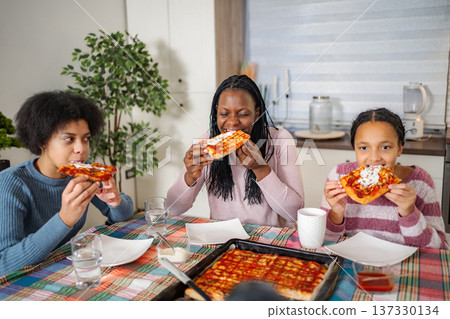 African American family eating homemade pizza together at home African American family eating homemade pizza together at home 137330134