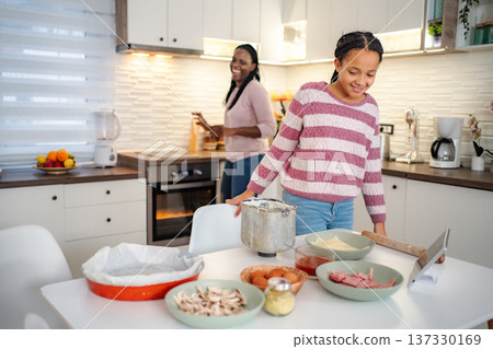 Mother and daughter baking together in kitchen watching tablet recipe 137330169